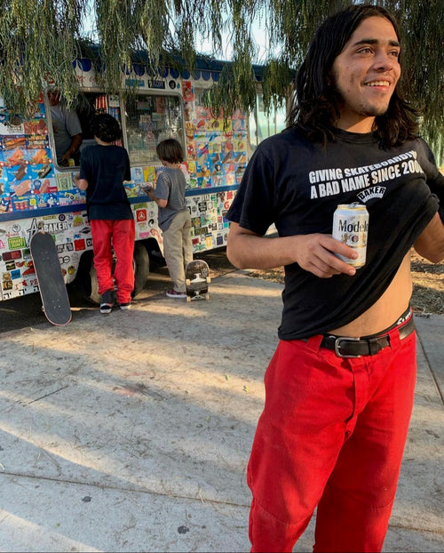 Angel Cisnerros standing and smiling in front of an ice cream truck with a "Modelo" in his hand