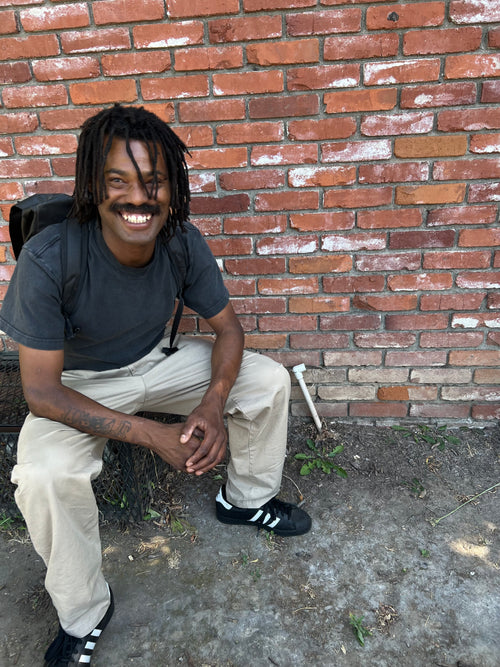 Tislam Smith sitting against a brick wall with a backpack