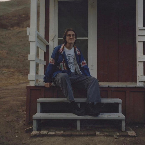 Sam Marino sitting on a wooden porch in front of a cabin.