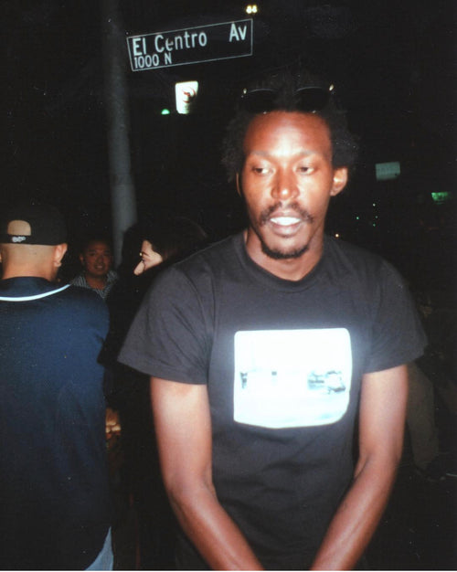 Lamare Hemmings wearing sunglasses on his head in front of an El Centro Av street sign at night