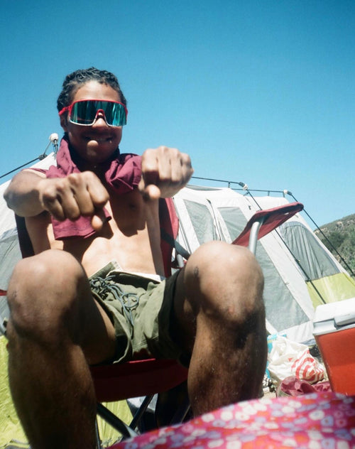 Manny Rowe sitting on a chair while wearing sunglasses in front of a tent