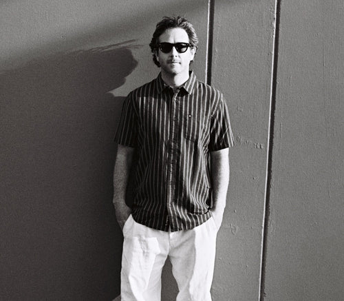 Harrison Gordon wearing sunglasses and a striped shirt against a plain background