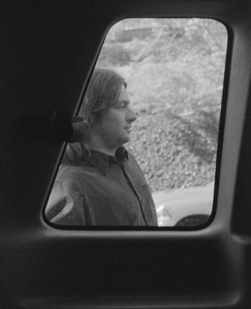 A black and white photo of Tristan Funkhouser standing outside of a window