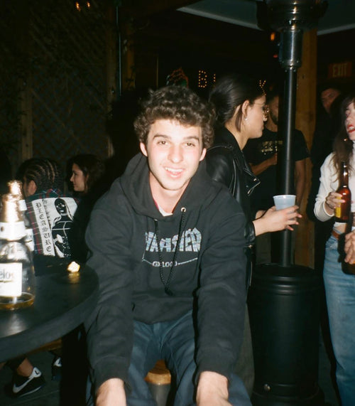 Tyler Pacheco sitting on a bar stool wearing a black "Thrasher" hooded sweatshirt